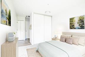 A bedroom with a bed, nightstand, and a painting on the wall.