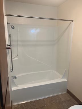 A shower with a glass door and a brown counter top.
