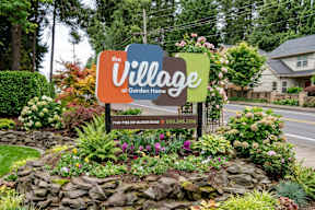 A sign for The Village at Garden Home with a phone number on it.