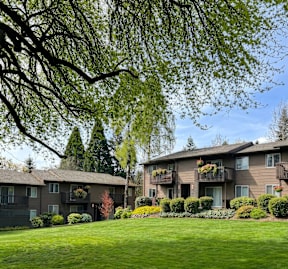 Apartment complex with green lawn and trees.