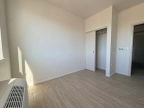 A room with a heater and wood flooring.