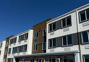 A modern multi-story residential building with balconies and large windows.