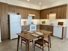 A kitchen with a table set for two with a refrigerator and oven in the background.