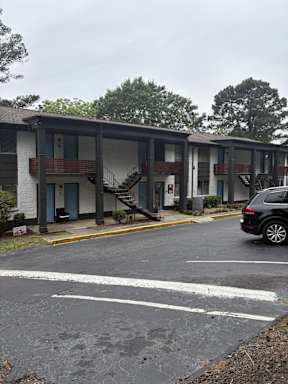 A black car is parked in a parking lot in front of a building.