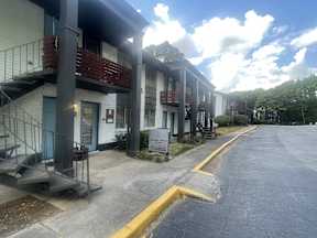 A row of apartment buildings with a blue sky and clouds in the background.
