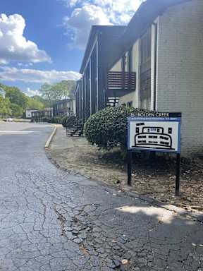 A sign for Bolden Creek stands in front of a building.