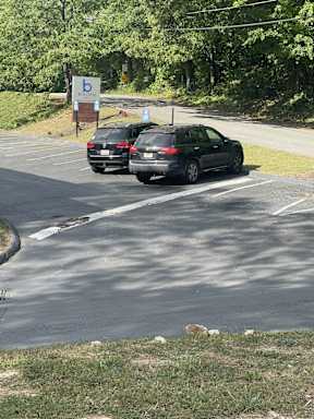 Two cars are parked in a parking lot with a sign that has a letter "b" on it.
