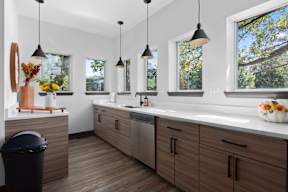 a kitchen with wooden cabinets and a large sink and windows