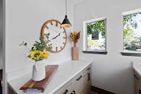 a kitchen counter with a clock and a vase of flowers