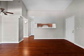 an empty living room with wood floors and a ceiling fan