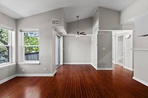 an empty living room with wood floors and a ceiling fan