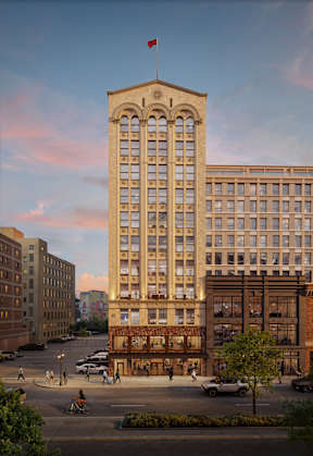 An exterior rendering of The Belle with a flag on top stands in front of other buildings.