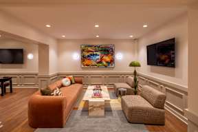 The community room at The Belle with a brown couch, a coffee table, and a painting on the wall.