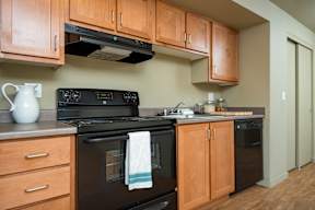 A kitchen with wooden cabinets and black appliances.