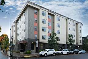 A modern apartment building with cars parked in front.