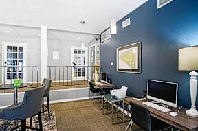 A room with a desk, chairs, and a balcony.