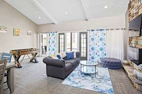 A living room with a grey couch, a wooden table, and a blue rug.