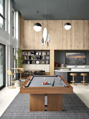 a living room with a pool table and a kitchen with a bar