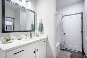 Bathroom with white cabinets, sink and large mirror located at Deforest Yards in DeForest, WI