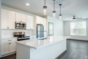 A modern kitchen with a white island and stainless steel appliances located at Deforest Yards apartments in DeForest, WI