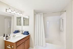 A bathroom with a sink, mirror, and shower