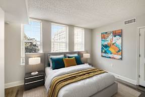 A bedroom with a large bed and a painting on the wall