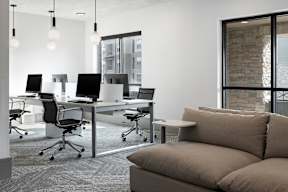 A modern office space with a couch, chairs, and desks.