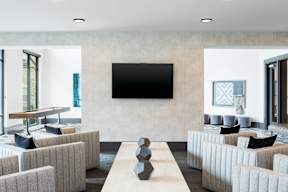 A modern living room with a large flat screen TV mounted on the wall.