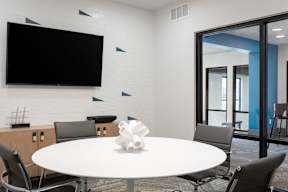 A white table with a vase on it and chairs around it.