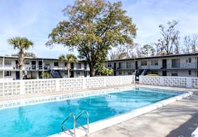Swimming pool in front of a building with trees in the background.