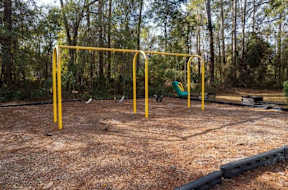 Yellow pull-up bar is in the middle of a dirt field.