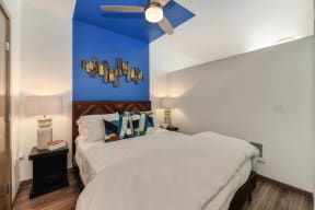 Bedroom  with Sliding Door, Hardwood Inspired Floor, White Comforter Bedding, Blue Wall and Ceiling Fan/Light