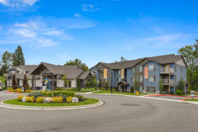 Entrance Round-About with Blue and Gray Apartment Exteriors, Road, Plants and Grass Covered Center