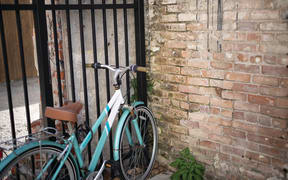 A green bike is leaning against a brick wall.