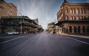 A street with buildings on either side and a car parked on the side of the road.
