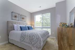 A bedroom with a large window, plush carpet flooring, and ample natural lighting. at Keva Flats, Pennsylvania
