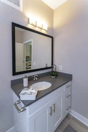 A bathroom sink with a large mirror, sink vanity with quartz countertops, and hardwood-style flooring. at Keva Flats, Exton, PA, 19341