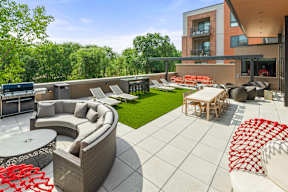 A roof-top terrace with a grilling station, fire pits, a comfortable seating area, chairs, tables, and lounge chairs on artificial turf. at Keva Flats, Pennsylvania