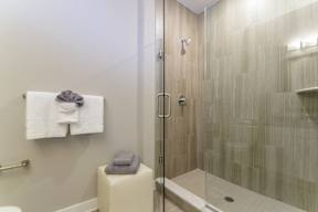 A bathroom with modern tile walls in a stand-up shower, a towel holder, and a stool with folded towels. at Keva Flats, Pennsylvania, 19341