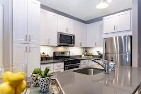 A well-lit modern kitchen with stainless steel appliances, white cabinets, subway tile backsplash, and under-cabinet lighting. at Keva Flats, Exton, PA, 19341