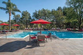 Pool with table and chairs Apartments in Pittsburg, CA l Kirker Creek Apartments