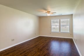an empty living room with wood floors and a ceiling fan
