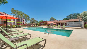 our apartments have a resort style pool with chairs and umbrellas at Spring Meadow Apartments, Arizona