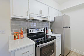 a kitchen with stainless steel appliances and white cabinets at Spring Meadow Apartments, Glendale, AZ
