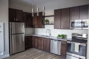a kitchen with dark wood cabinets and stainless steel appliances  at RoCo Apartments, North Dakota