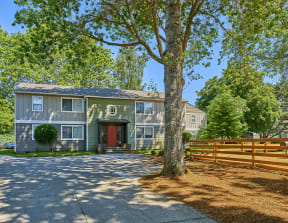 Exterior view of community. Shows a large tree along with wooded area.at Woodhaven, Everett