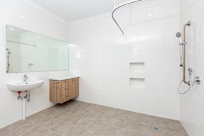 A white bathroom with a sink, mirror, and shower.
