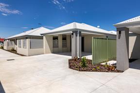 A row of modern houses with white roofs and grey walls.