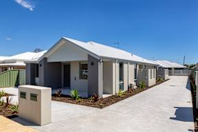A series of modern houses with white roofs and grey walls.