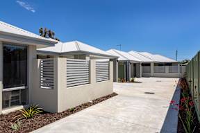 A row of houses with white roofs and grey walls.